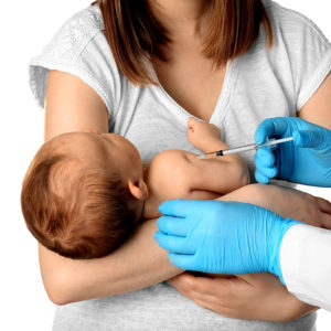 anne kucağında aşı yapılan bebek