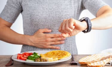 a person with a watch on her hand looking at a plate of food